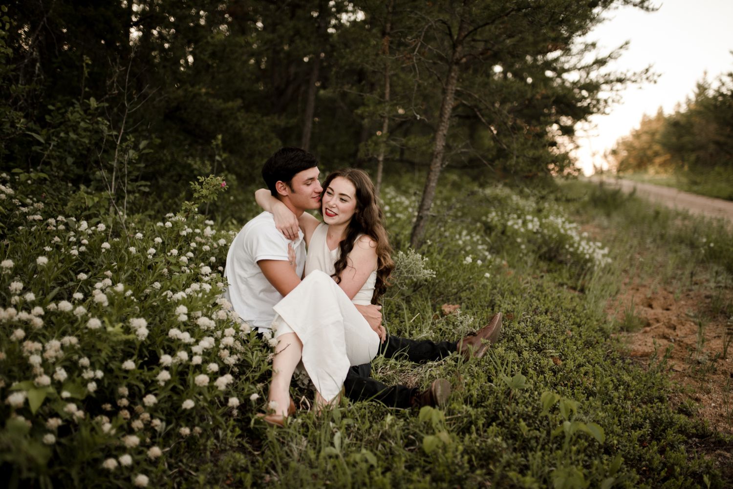 girl and her husband sitting in a field of flowers for their winnipeg engagement photos. Images taken by Vanessa Renae Photography, a winnipeg engagement photographer