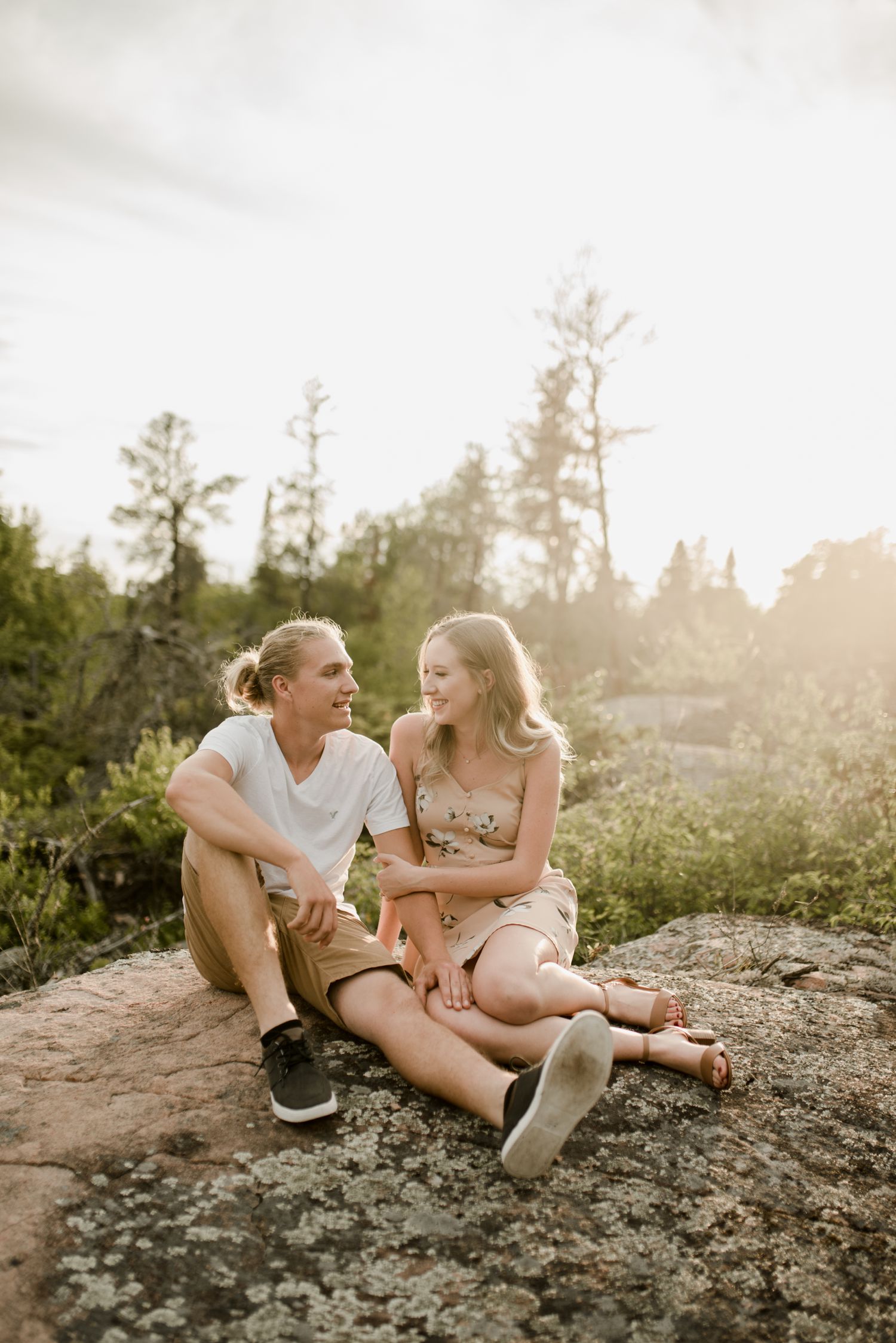 engaged couple sitting on a rock together on their whiteshell engagement shoot. Photos by Vanessa Renae Photography, a Winnipeg and Kenora wedding photographer