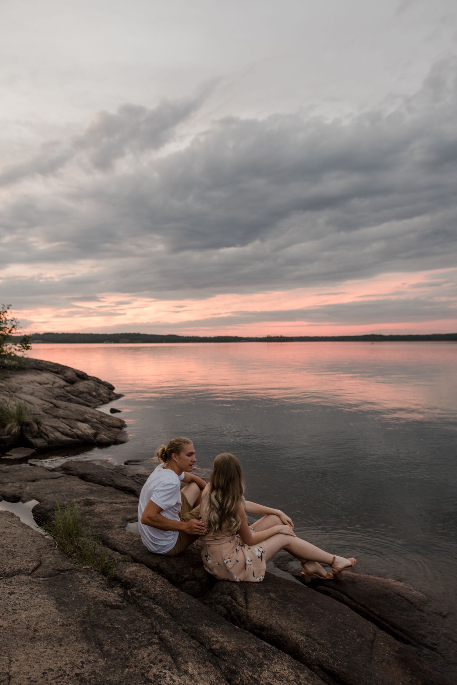 engaged couple sitting on a rock together on their whiteshell engagement shoot. Photos by Vanessa Renae Photography, a Winnipeg and Kenora wedding photographer