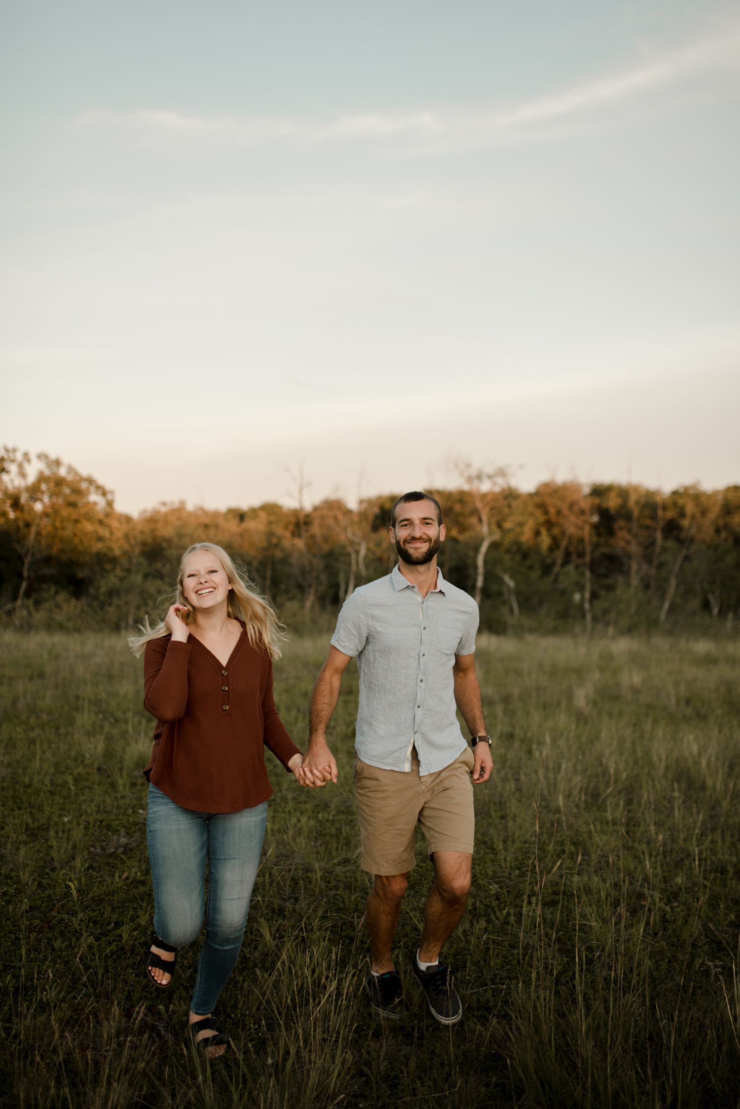 couple running around on a field for their Winnipeg anniversary session, photographed by Vanessa Renae Photography.