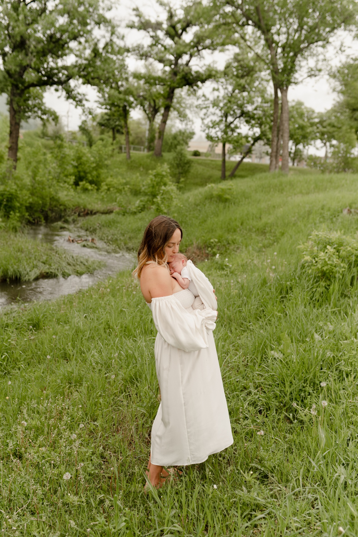 Winnipeg outdoor newborn family session with mom holding baby wearing a white silk client closet dress